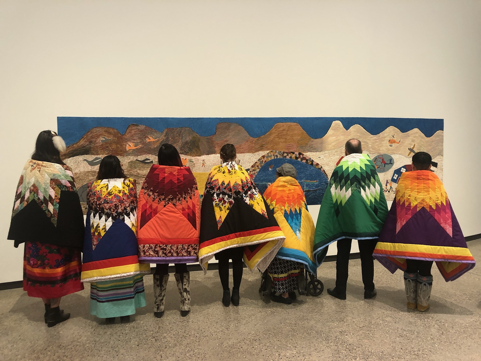 A group of people with blankets on their shoulders, participating in the Star Blanket Ceremony. 
