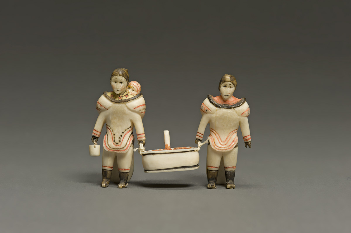 An ivory Inuit carving by an unknown artist of two women carrying meat in a tub.