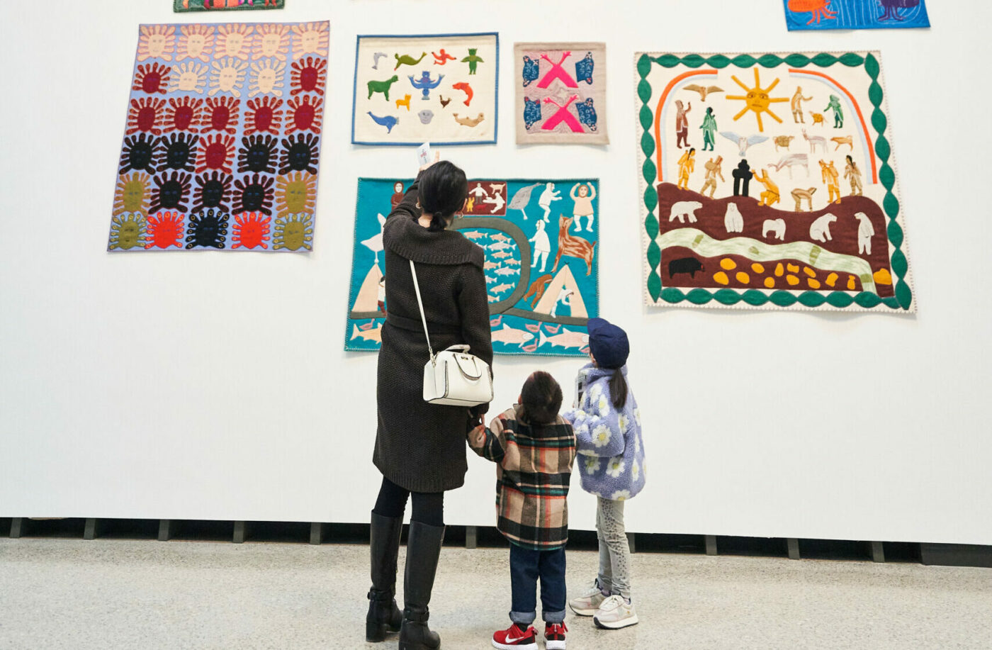 A family stands and looks at art in the Winnipeg Art Gallery-Qaumajuq.